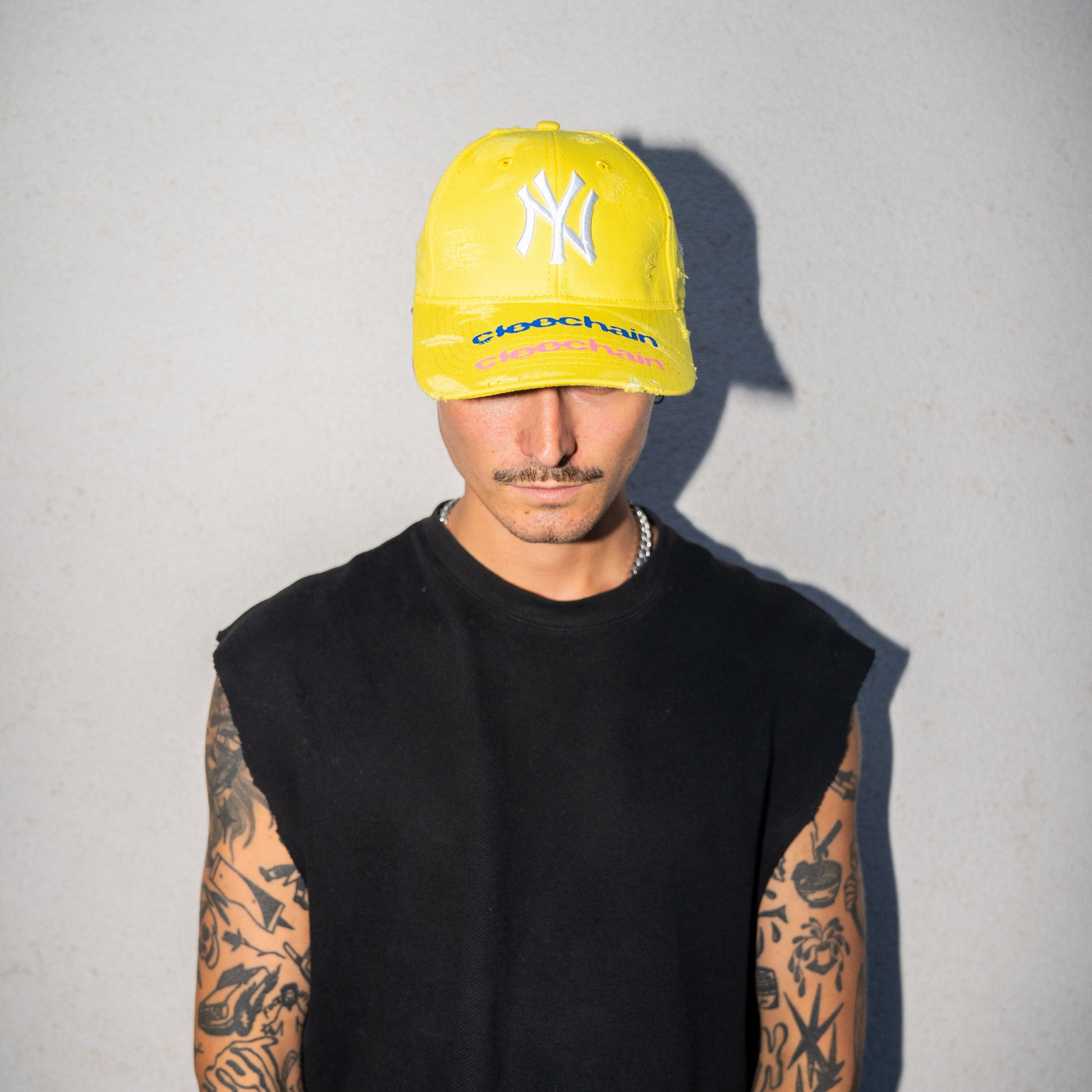 Person wearing a yellow cap with a logo on a plain background