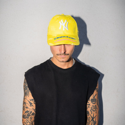 Person wearing a yellow cap with a logo on a plain background